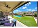 Covered patio view of an inviting backyard with a pool, putting green, desert landscaping, and mountain views at 16389 W Fawn Dr, Goodyear, AZ 85338