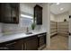 Modern kitchen featuring wine fridge, dark cabinets, light countertops, adjacent to walk-in pantry at 16389 W Fawn Dr, Goodyear, AZ 85338