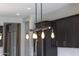 Modern kitchen with striking pendant lighting fixtures contrasted by dark cabinets and stainless appliances at 16389 W Fawn Dr, Goodyear, AZ 85338