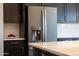 Modern kitchen featuring a stainless steel refrigerator, contrasted by dark cabinets and white backsplash at 16389 W Fawn Dr, Goodyear, AZ 85338