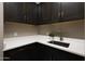 Modern laundry room featuring elegant dark wood cabinets and sleek white countertops at 16389 W Fawn Dr, Goodyear, AZ 85338