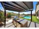 Outdoor kitchen with built in BBQ, set beneath a pergola and overlooking a sparkling pool and desert landscape at 16389 W Fawn Dr, Goodyear, AZ 85338