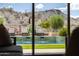 A view of a sparkling backyard pool surrounded by lush greenery, as seen from inside the home at 16389 W Fawn Dr, Goodyear, AZ 85338