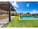 Inviting backyard oasis featuring a sparkling pool, artificial turf, outdoor kitchen and a covered pergola at 16389 W Fawn Dr, Goodyear, AZ 85338