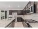 Modern kitchen with an island, dark wood cabinets, granite countertops, subway tile backsplash, and stainless steel appliances at 17376 W Via De Luna Dr, Surprise, AZ 85387