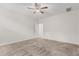 Spacious primary bedroom with neutral carpet, ceiling fan, and a view into the bathroom and walk in closet at 17376 W Via De Luna Dr, Surprise, AZ 85387