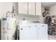 Laundry room featuring a water heater, washer and dryer, and white cabinets at 17804 N Del Webb Blvd, Sun City, AZ 85373