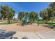 Community playground with climbing structures and a slide, surrounded by trees and sand at 17836 N 52Nd Pl, Scottsdale, AZ 85254