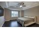Spacious bedroom featuring dark hardwood floors, tray ceiling with fan, and white shutters on the window at 18515 N 97Th Way, Scottsdale, AZ 85255