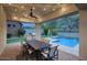 An outdoor dining area on a covered patio with a pool view is lit by string lights at 18515 N 97Th Way, Scottsdale, AZ 85255