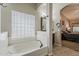 Soaking tub in bathroom featuring a vanity area and a view to the main bedroom at 18581 E Aubrey Glen Rd, Queen Creek, AZ 85142