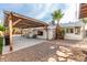Inviting backyard featuring a covered patio, palm tree, and rock landscaping at 2001 W Surrey Ave, Phoenix, AZ 85029