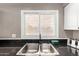 Close up view of a stainless steel double basin sink with black countertops and a window at 2001 W Surrey Ave, Phoenix, AZ 85029