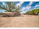 Dirt backyard featuring several storage buildings, a motorcycle, and solar panels at 2024 N 200Th Ave, Buckeye, AZ 85396