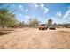 Spacious dirt backyard featuring a truck and car parked under a sunny blue sky at 2024 N 200Th Ave, Buckeye, AZ 85396