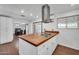 Open kitchen with butcher block island, white cabinets, stainless steel vent hood and view to dining area at 2024 N 200Th Ave, Buckeye, AZ 85396