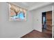 Empty bonus room with neutral walls, vinyl floors, window and view to another room with wood paneling at 2024 N 200Th Ave, Buckeye, AZ 85396