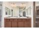 Bathroom with double sink vanity, lots of lighting and a glimpse of the tiled shower at 20261 W Desert Bloom St, Buckeye, AZ 85326