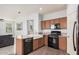 Kitchen featuring a farmhouse sink, dark appliances, and bar seating open to the living area at 20261 W Desert Bloom St, Buckeye, AZ 85326