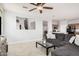 Cozy living room featuring gray couches, modern fan, wood-look tile floors, and ample natural light at 20261 W Desert Bloom St, Buckeye, AZ 85326