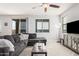 Relaxing living room with gray couches, wood-look tile floors, a modern ceiling fan and big window at 20261 W Desert Bloom St, Buckeye, AZ 85326