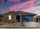 Attractive single-story home with desert landscaping and a blue garage door set against a colorful sky at 20368 N 224Th Dr, Surprise, AZ 85387