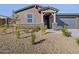 Inviting front yard with desert landscaping, a stone accent wall, and a covered entryway at 20368 N 224Th Dr, Surprise, AZ 85387