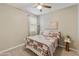 Comfortable bedroom with a patterned comforter, ceiling fan, and neutral walls at 21690 N Lynn St, Maricopa, AZ 85138