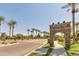 Rancho El Dorado community entrance boasts a stone sign, palm trees, and well-maintained landscaping along a paved road at 21690 N Lynn St, Maricopa, AZ 85138