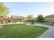 Serene backyard featuring lush green lawn, mature landscaping, a water feature and a stone pathway at 2211 W Desert Ln, Phoenix, AZ 85041
