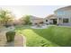 Backyard view of a lawn, fountain, patio, and a two-story house with a gray exterior and tile roof at 2211 W Desert Ln, Phoenix, AZ 85041