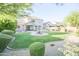 Expansive backyard with a lush lawn, mature trees, rock features, and a large covered patio at 2211 W Desert Ln, Phoenix, AZ 85041