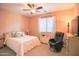 A bright, carpeted bedroom with a ceiling fan, Queen bed, and a comfortable black leather chair at 2211 W Desert Ln, Phoenix, AZ 85041