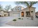 Two-story home with a three-car garage, covered porch, desert landscaping, and a driveway with parked cars at 2211 W Desert Ln, Phoenix, AZ 85041