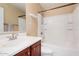 This bathroom features cherry-look cabinets, a large mirror, and a white tub and shower combo at 22123 E Vía Del Palo --, Queen Creek, AZ 85142