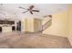 Spacious living room with carpeted floors, ceiling fan, and seamless transition to the kitchen and staircase at 22123 E Vía Del Palo --, Queen Creek, AZ 85142