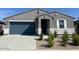 Charming single-story home featuring a blue garage door and low-maintenance desert landscaping at 22490 W Tonopah Dr, Surprise, AZ 85387