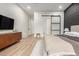 Spacious bedroom featuring sleek wood floors, an accent wall, and ample storage with a sliding door to the bathroom at 22609 E Roundup Way, Queen Creek, AZ 85142