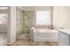 Beautiful bathroom featuring a glass enclosed shower, soaking tub, tile flooring, and a glass block window at 2503 E Camellia Dr, Gilbert, AZ 85296
