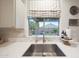 A kitchen sink features stainless steel fixtures and a window view to the backyard, with marble tile backsplash at 29966 N 72Nd Dr, Peoria, AZ 85383