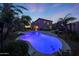 An illuminated backyard swimming pool and hot tub feature landscaping and a spacious patio at twilight at 29966 N 72Nd Dr, Peoria, AZ 85383