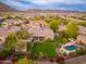 The aerial view shows the backyard with a sparkling pool, lush grass, mature trees, and a covered patio at 31900 N 127Th Ln, Peoria, AZ 85383