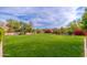 Expansive backyard with lush green grass, mature trees, vibrant flowerbeds, and a swimming pool at 31900 N 127Th Ln, Peoria, AZ 85383