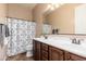 Bathroom featuring double sinks, a patterned shower curtain, and wood cabinets at 31900 N 127Th Ln, Peoria, AZ 85383