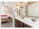 Bright bathroom featuring a double sink vanity with dark wood cabinets, and a view into the bedroom at 31900 N 127Th Ln, Peoria, AZ 85383