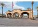 Elegant community entrance gate with stone arches, manicured landscaping, and an American flag at 31900 N 127Th Ln, Peoria, AZ 85383