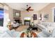 Cozy living room with a stone fireplace, comfortable seating, a ceiling fan, and natural light at 31900 N 127Th Ln, Peoria, AZ 85383