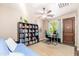 Well-lit home office with a ceiling fan, desk setup, and a large bookshelf for storage and decor at 31900 N 127Th Ln, Peoria, AZ 85383