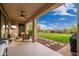 Covered patio with outdoor furniture and a TV, overlooking a lush, well-manicured backyard at 31900 N 127Th Ln, Peoria, AZ 85383