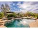 Inviting pool and spa area with lush landscaping and comfortable lounge seating, creating a private backyard oasis at 31900 N 127Th Ln, Peoria, AZ 85383